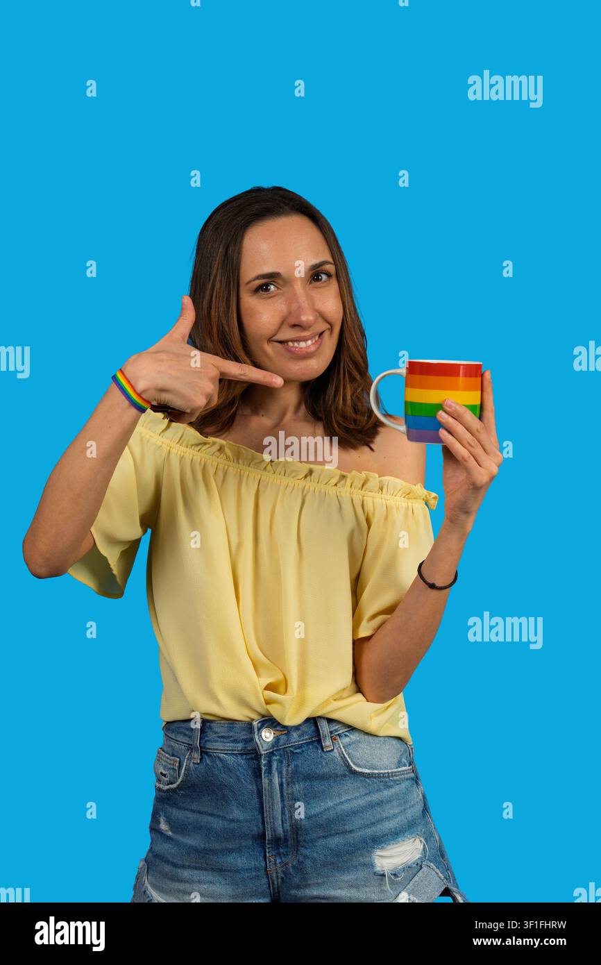 Woman smiling, highlighting a rainbow colored mug and wristband, expressing pride Stock Photo