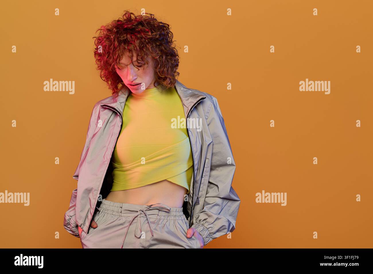 A stunning young woman with red curls displays her chic style in a vibrant setting. Stock Photo