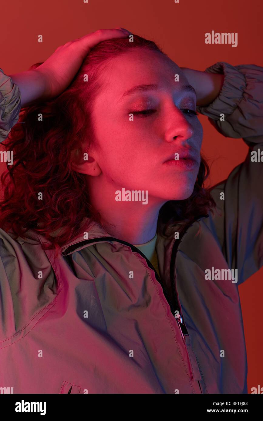 A young woman with stunning red curls poses elegantly, exuding confidence and style. Stock Photo