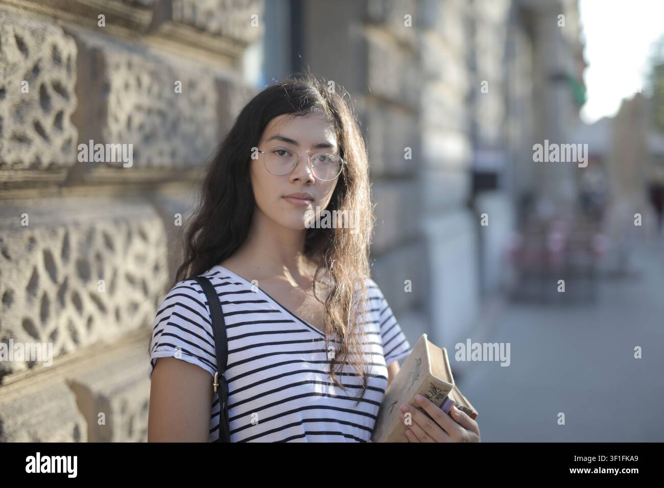 Thoughtful female student holding a book outdoors Stock Photo