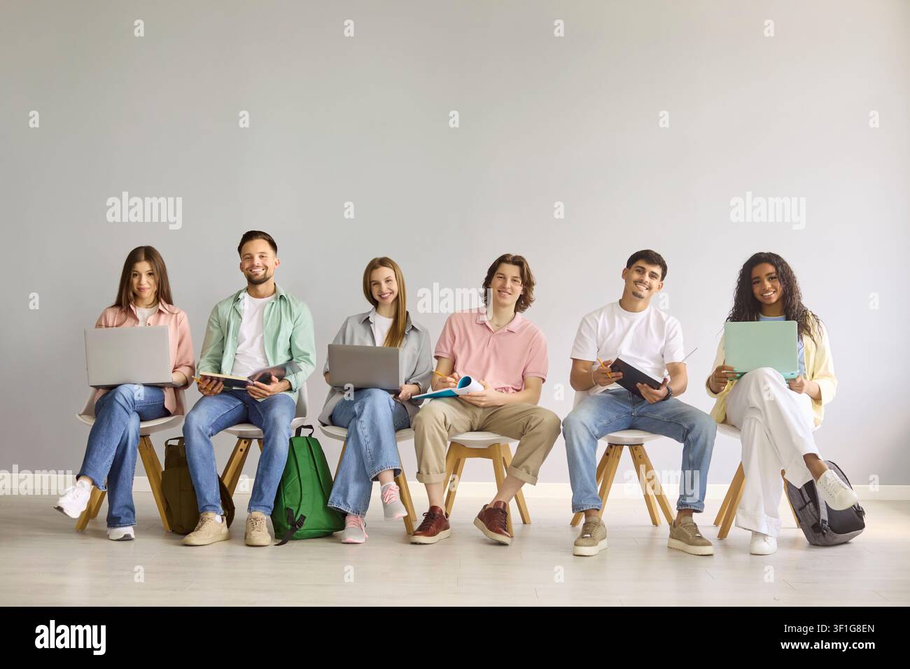 Happy students with laptops in classroom against gray background, teamwork Stock Photo