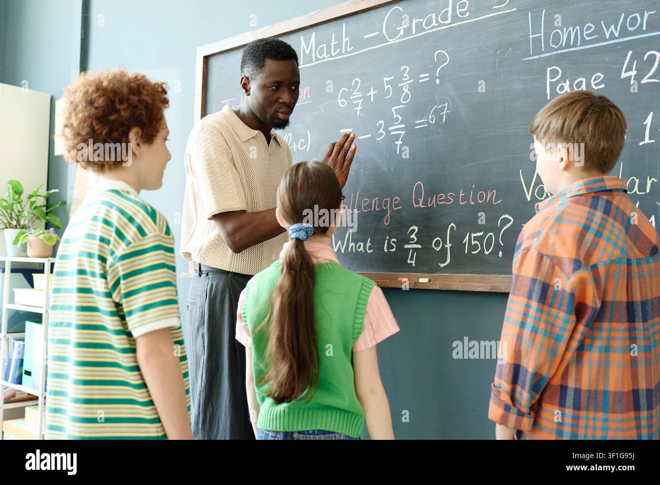 Black Male Teacher Explaining Math Problem to School Children Stock Photo