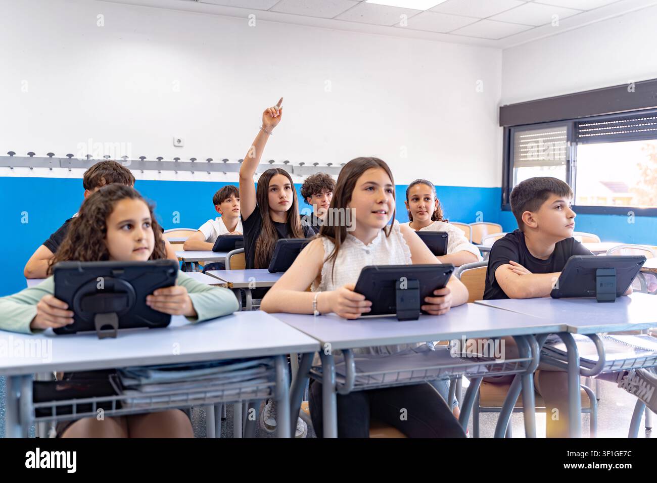School children using digital tablets for education, actively participating in a modern classroom environment, embracing e learning Stock Photo