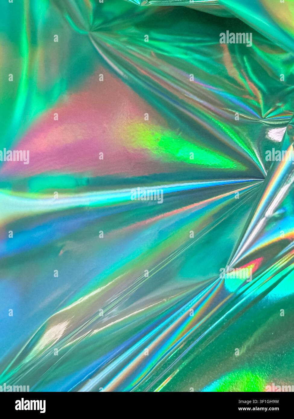 Abstract iridescent foil creating vibrant colorful reflections. Smooth glossy surface with light scattering. Dynamic visual texture suitable for moder Stock Photo
