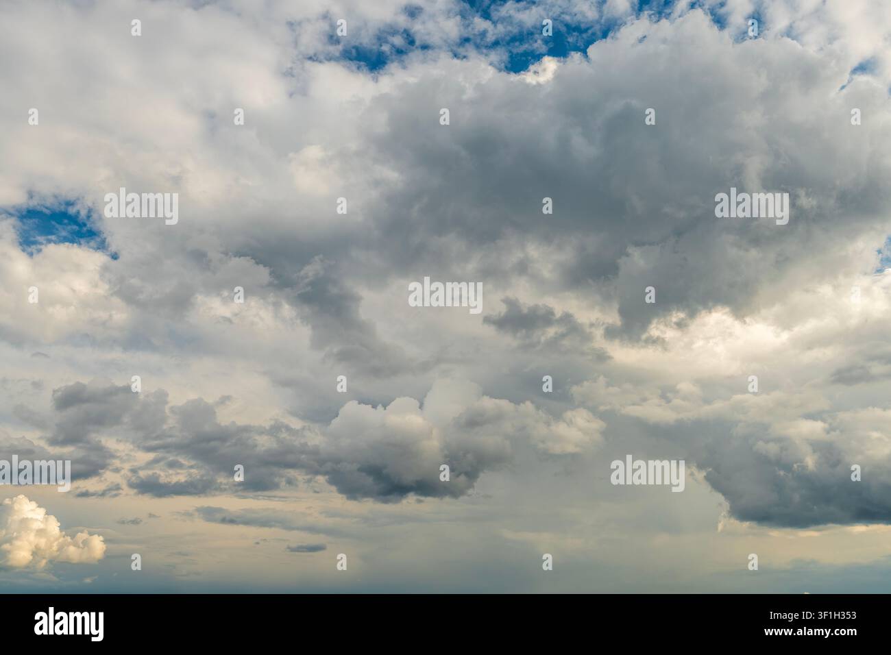 Dramatic storm clouds spreading across blue sky before rain Stock Photo