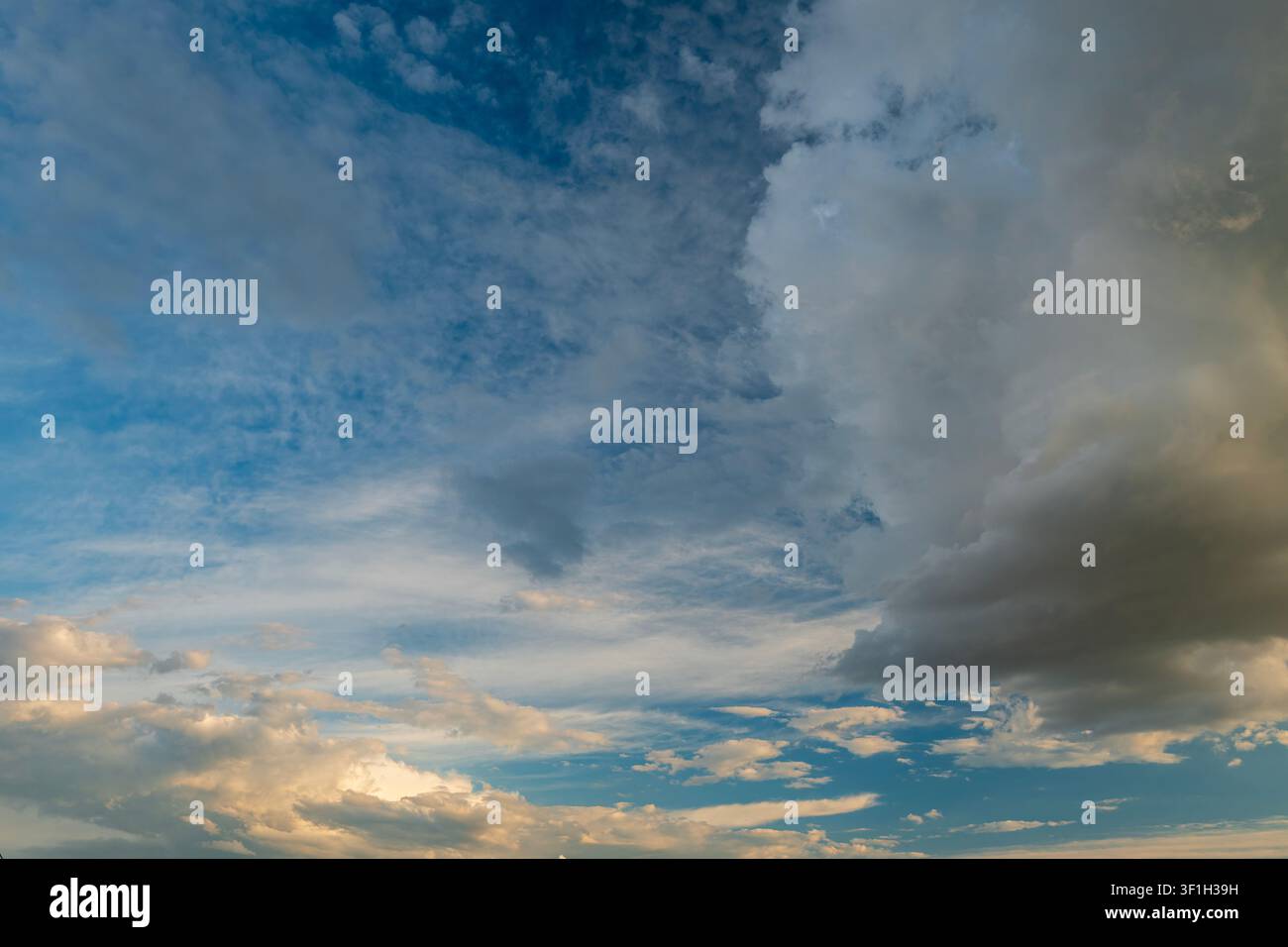 Dramatic sunset sky with dark cumulus and golden orange clouds Stock Photo