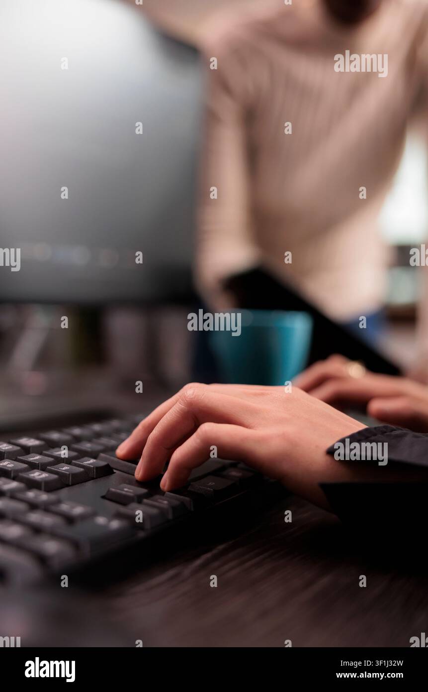 Programming team types machine learning code at a computer desk in an IT security agency, working together on databases, HTML script and software tasks. Stock Photo