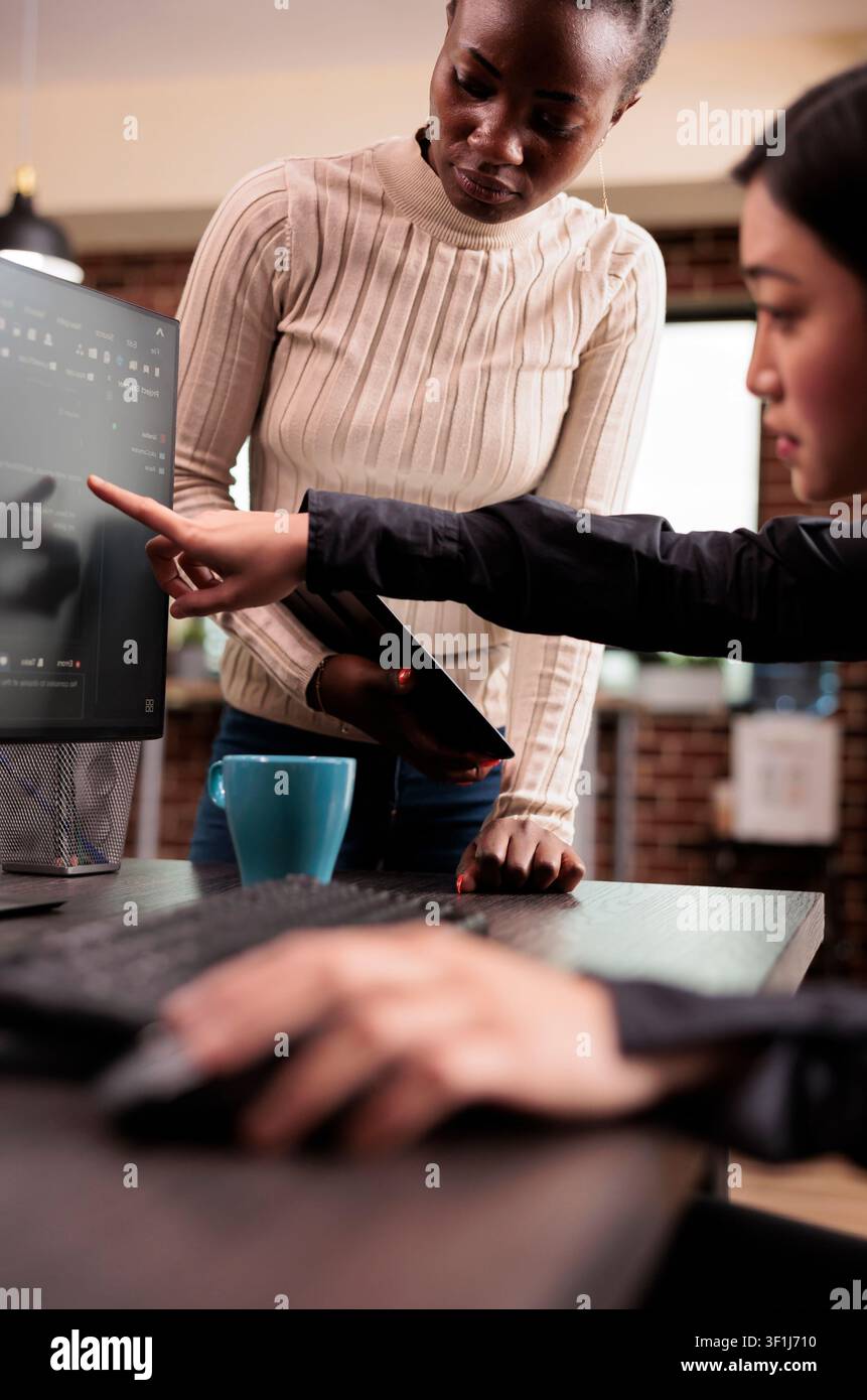 Team of software developers discussing source code at an IT office desk, using screens, scripts and cloud computing tools for software engineering workflow. Stock Photo