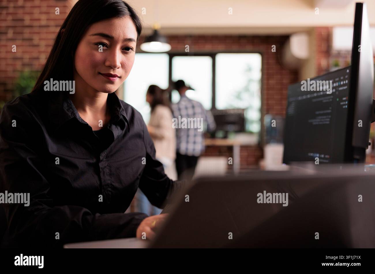 Asian freelance coder analyzes compiling HTML code on a monitor, working on interface development and programming tasks in an agency. Stock Photo