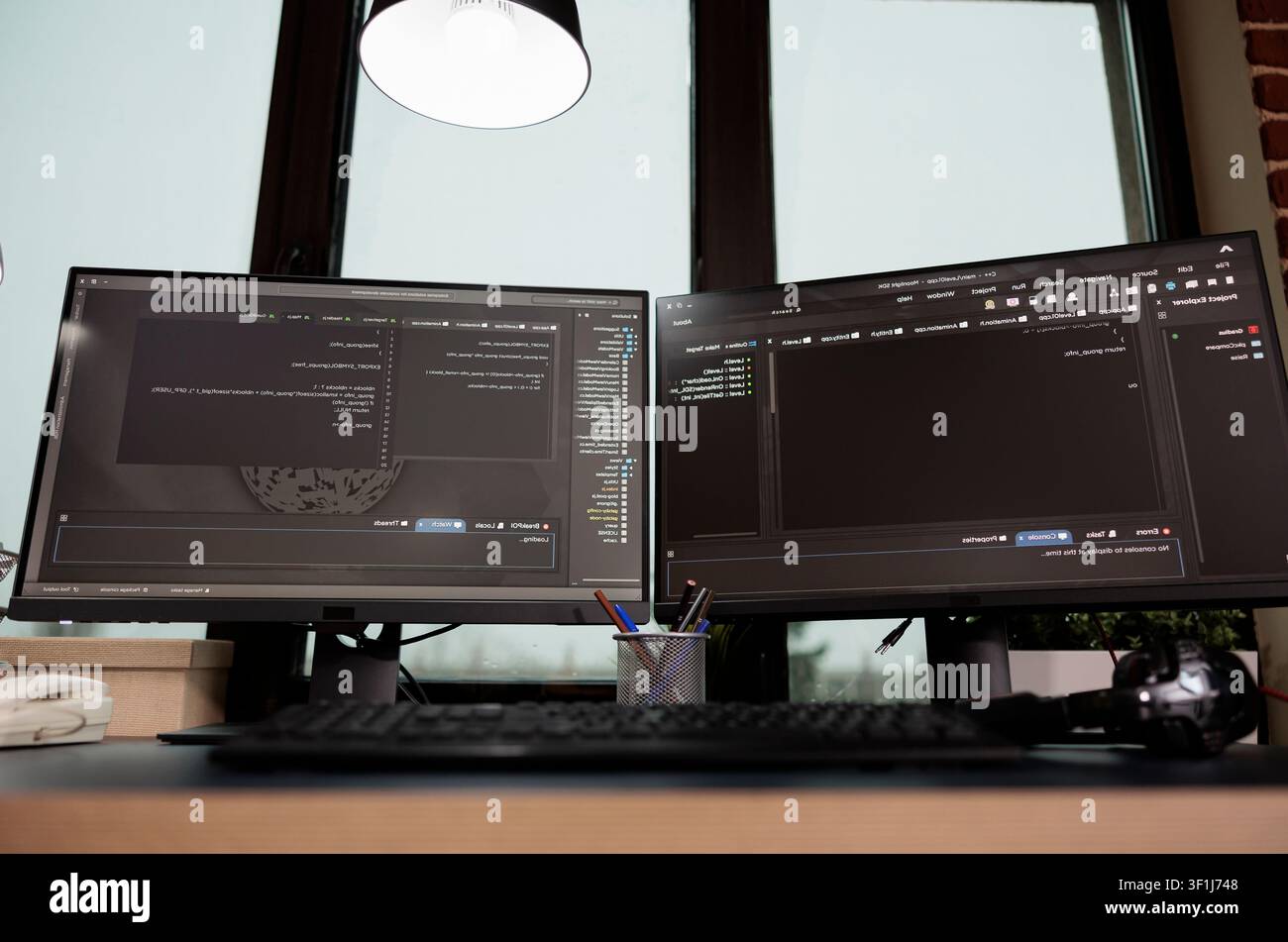 Multiple empty office monitors display programming code and algorithm data, showing software development work inside an IT agency. Stock Photo