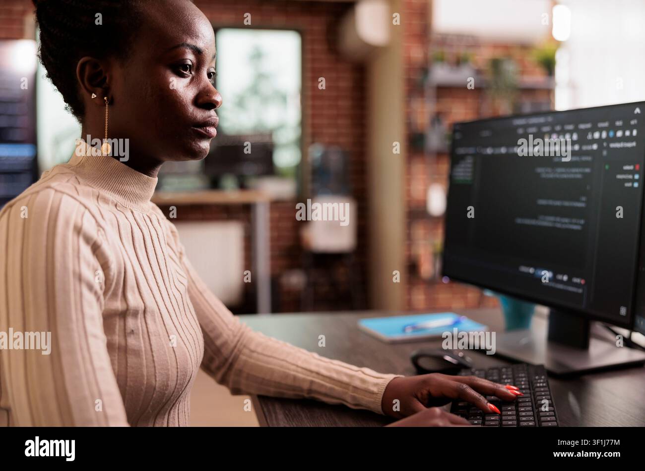 African American programmer sits at a computer typing big data code, developing HTML script and artificial intelligence algorithms in a programming agency. Stock Photo