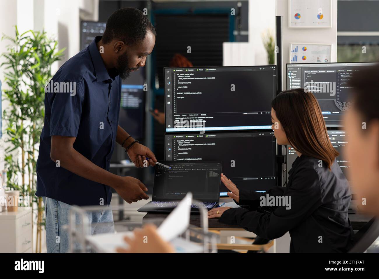 Diverse programmers work together in office, reviewing HTML code on multiple screens. Male and female developers plan digital solutions, improving app functionality through collaboration and innovation Stock Photo