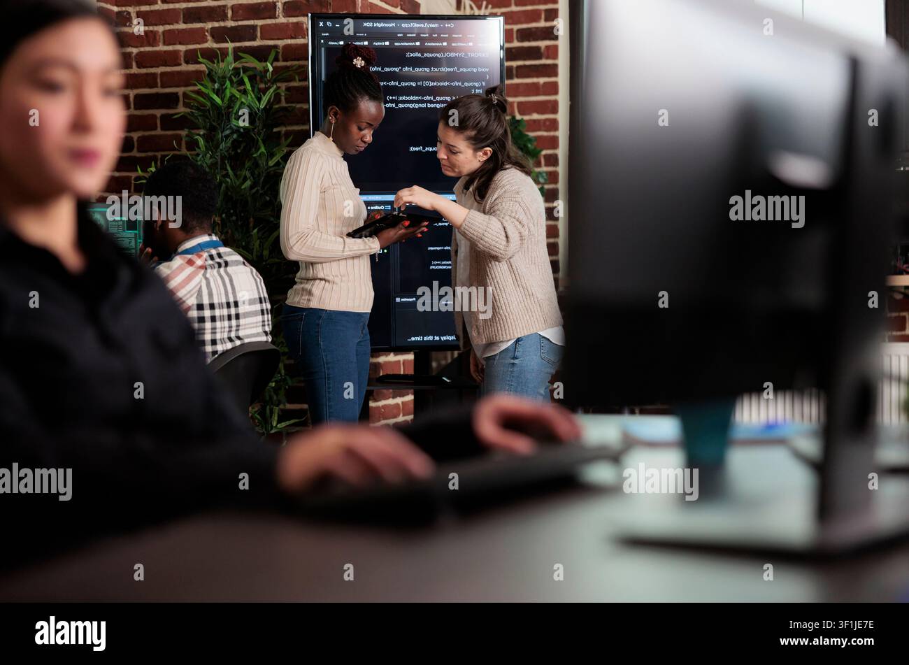 Software engineers discuss a cloud storage problem while reviewing code, database performance and artificial intelligence ideas in a programming office. Stock Photo