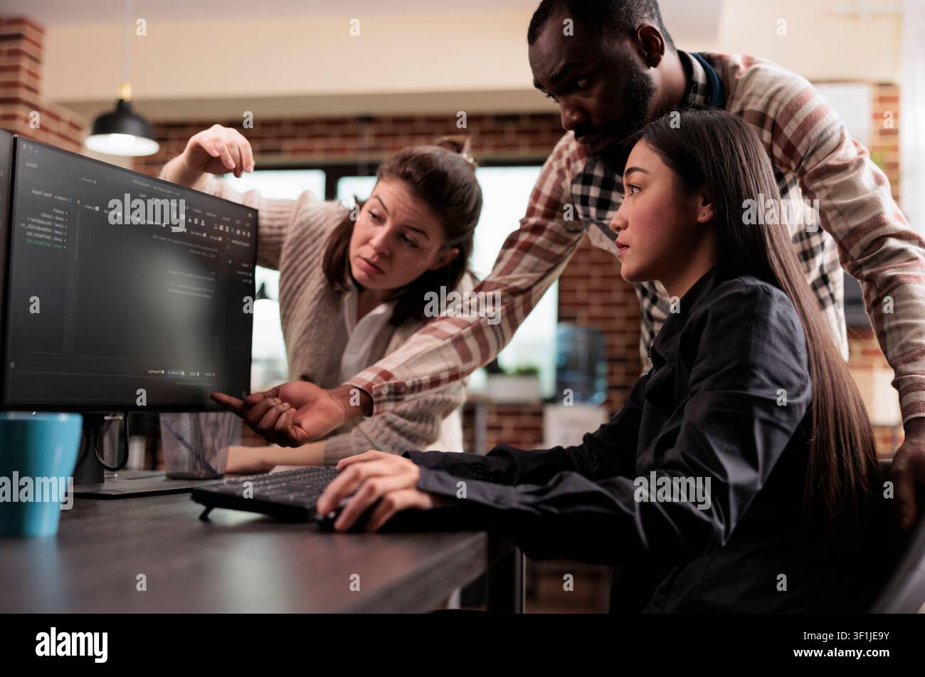 Multiethnic cybersecurity team works on encrypting a mainframe database and developing firewall protection after a system breach, inside a software security workflow. Stock Photo