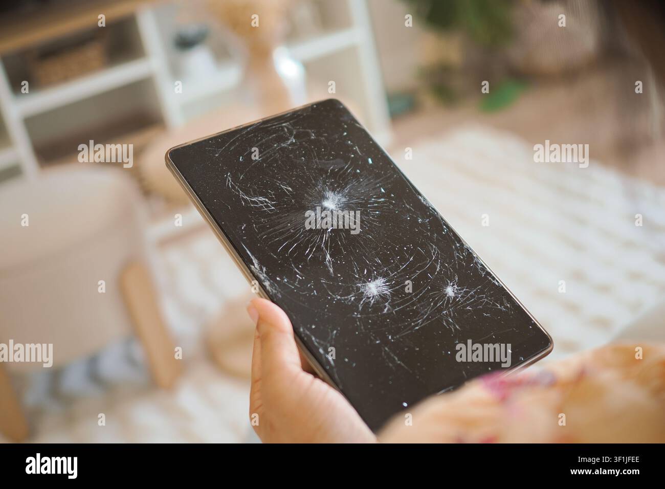 Broken tablet screen in a living room setting Stock Photo
