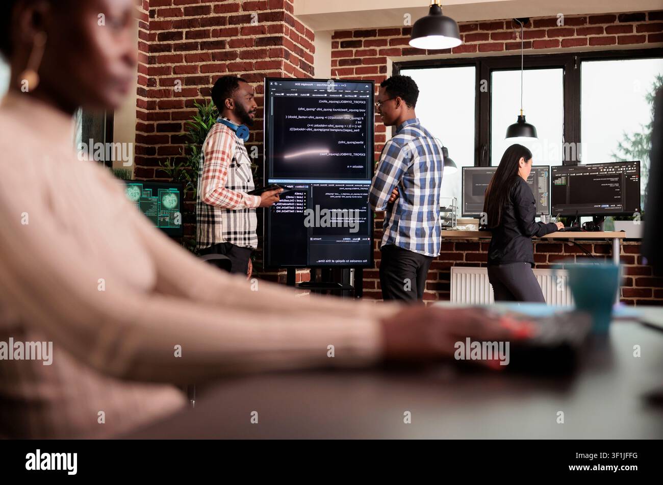 Two programming engineers examine HTML code on a large screen, checking errors in an artificial intelligence project for a technology company. Stock Photo