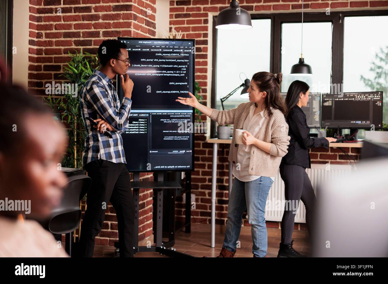 Diverse software developers collaborate on an IT project, coding company network systems and reviewing technical updates together. Stock Photo