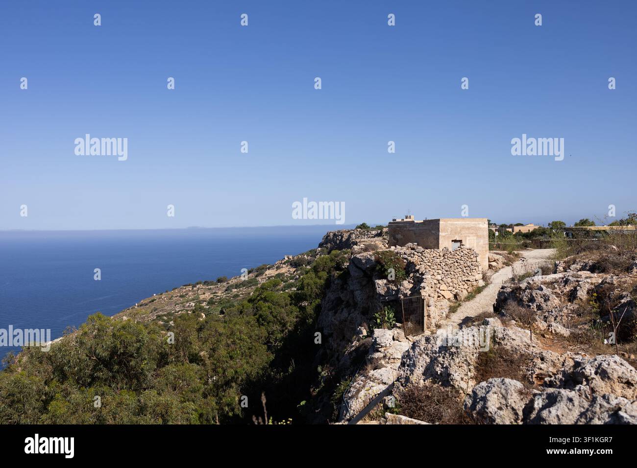 Old stone building on a rocky cliff edge with a scenic view of the mediterranean sea. Stock Photo