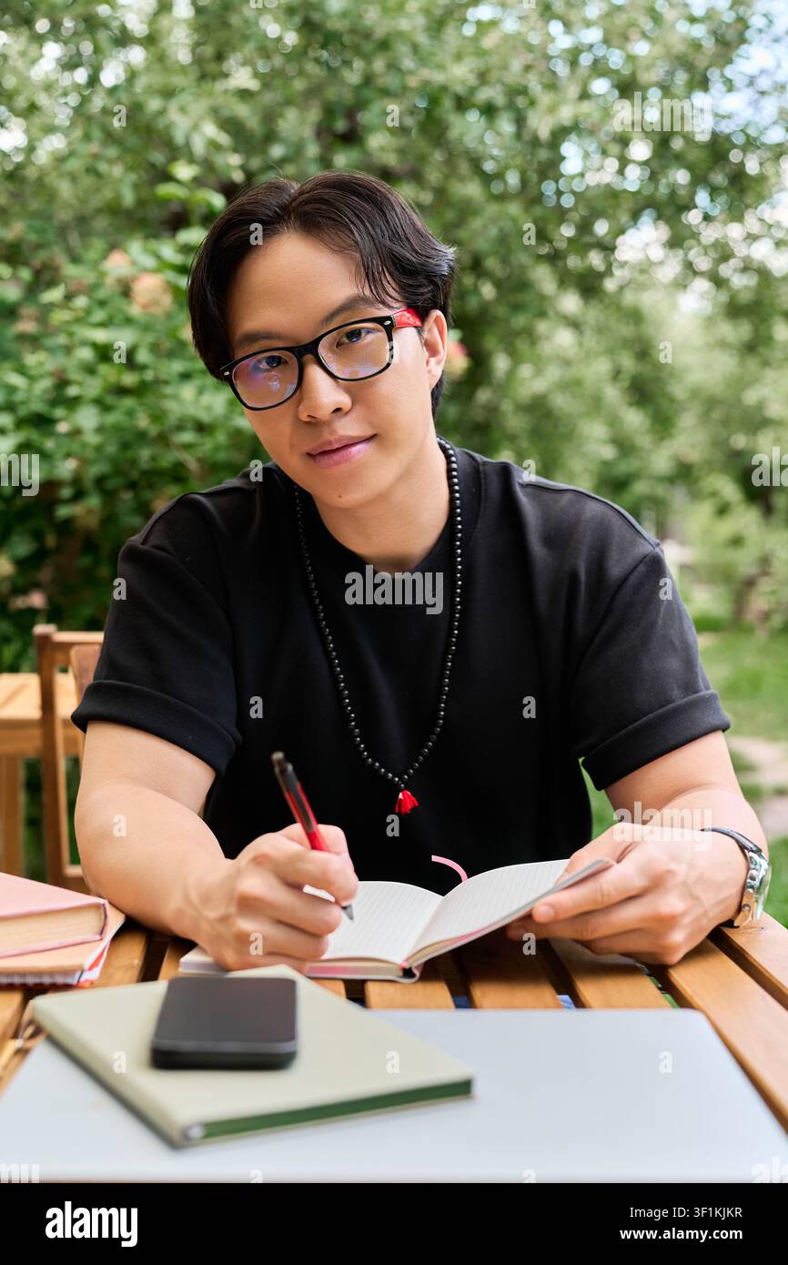 Young asian man immersed in work, capturing ideas on a notepad Stock Photo