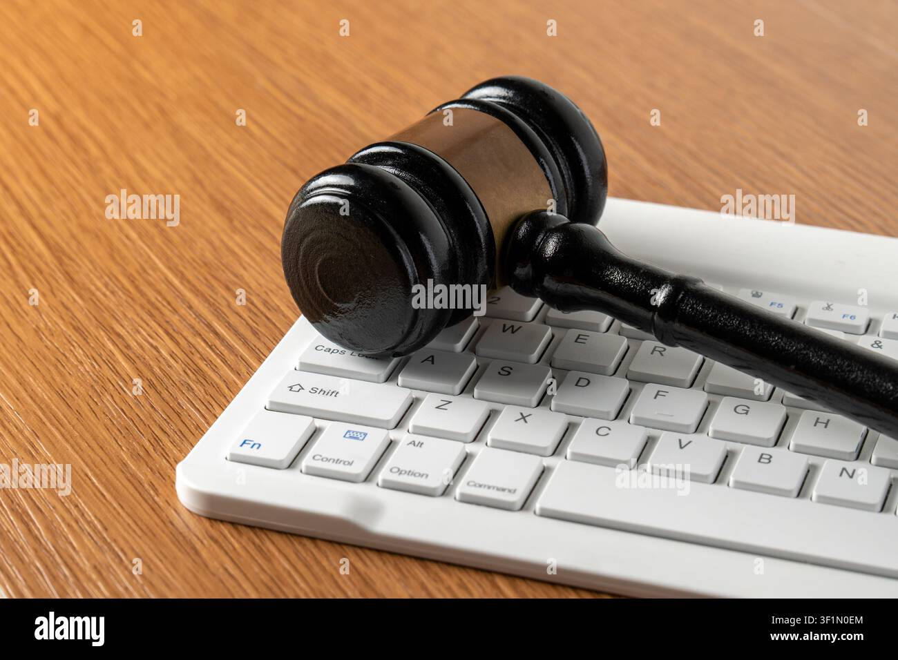 Wooden judge gavel on a white computer keyboard. Cyber law, digital justice, online crime, internet regulations concept. Stock Photo