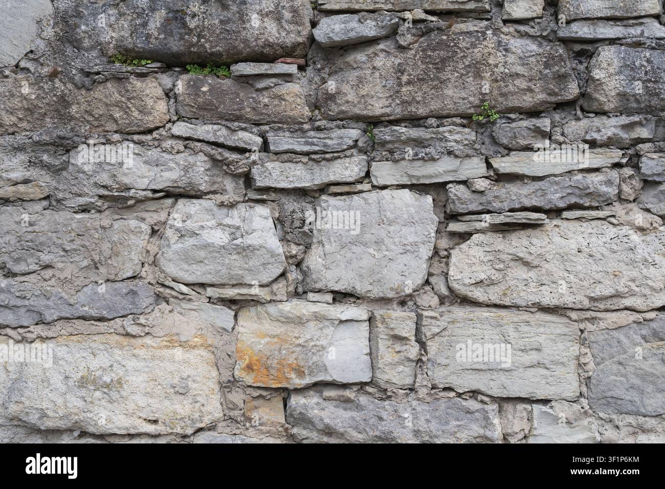 Weathered stone wall built from irregular natural rocks and mortar. Rustic masonry texture for architecture, restoration and design. Stock Photo