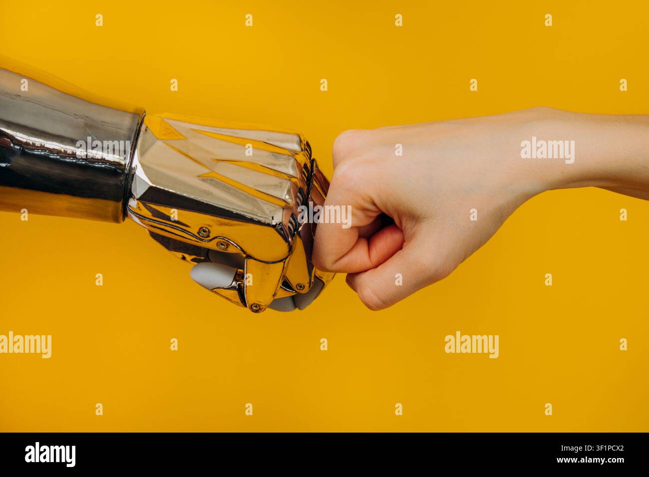 Human and robotic hands joining in a fist bump, representing innovative collaboration, the merging of human and artificial intelligence, and cutting edge technological partnership Stock Photo