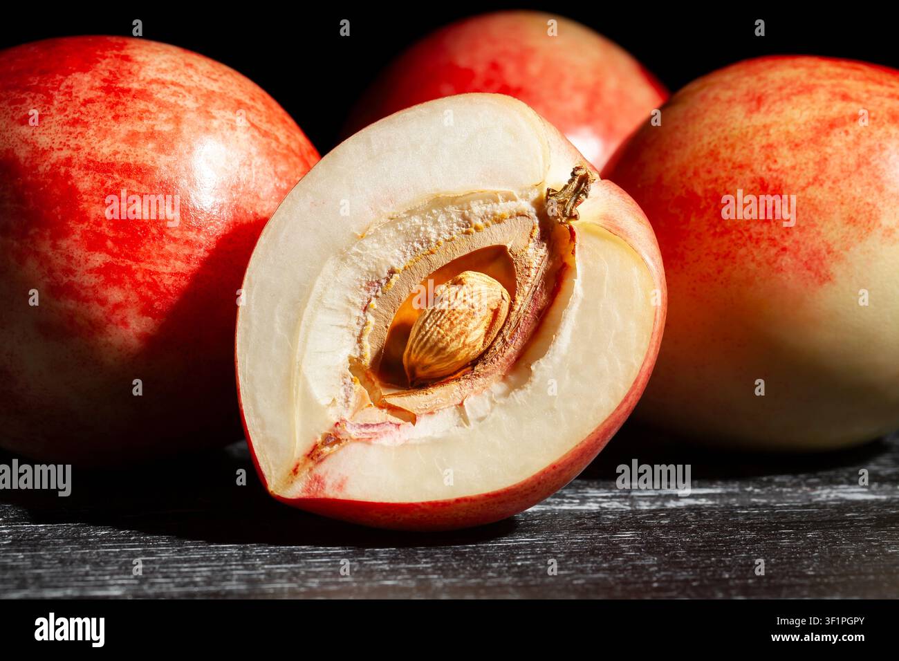 sliced white nectarine on black wood background Stock Photo