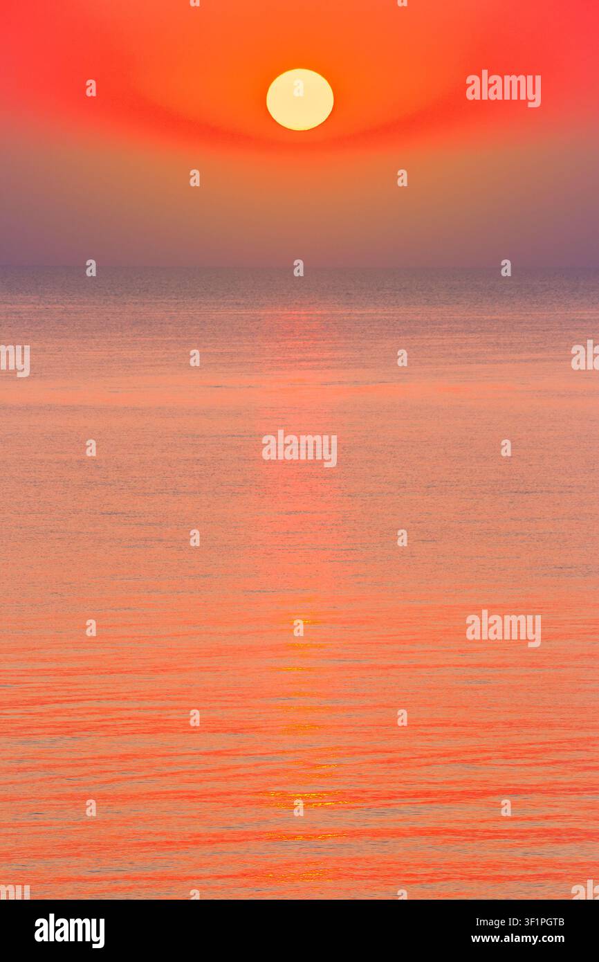 sunrise at the black sea. sun above horizon. reflection on the calm water. nature background in warm orange light Stock Photo