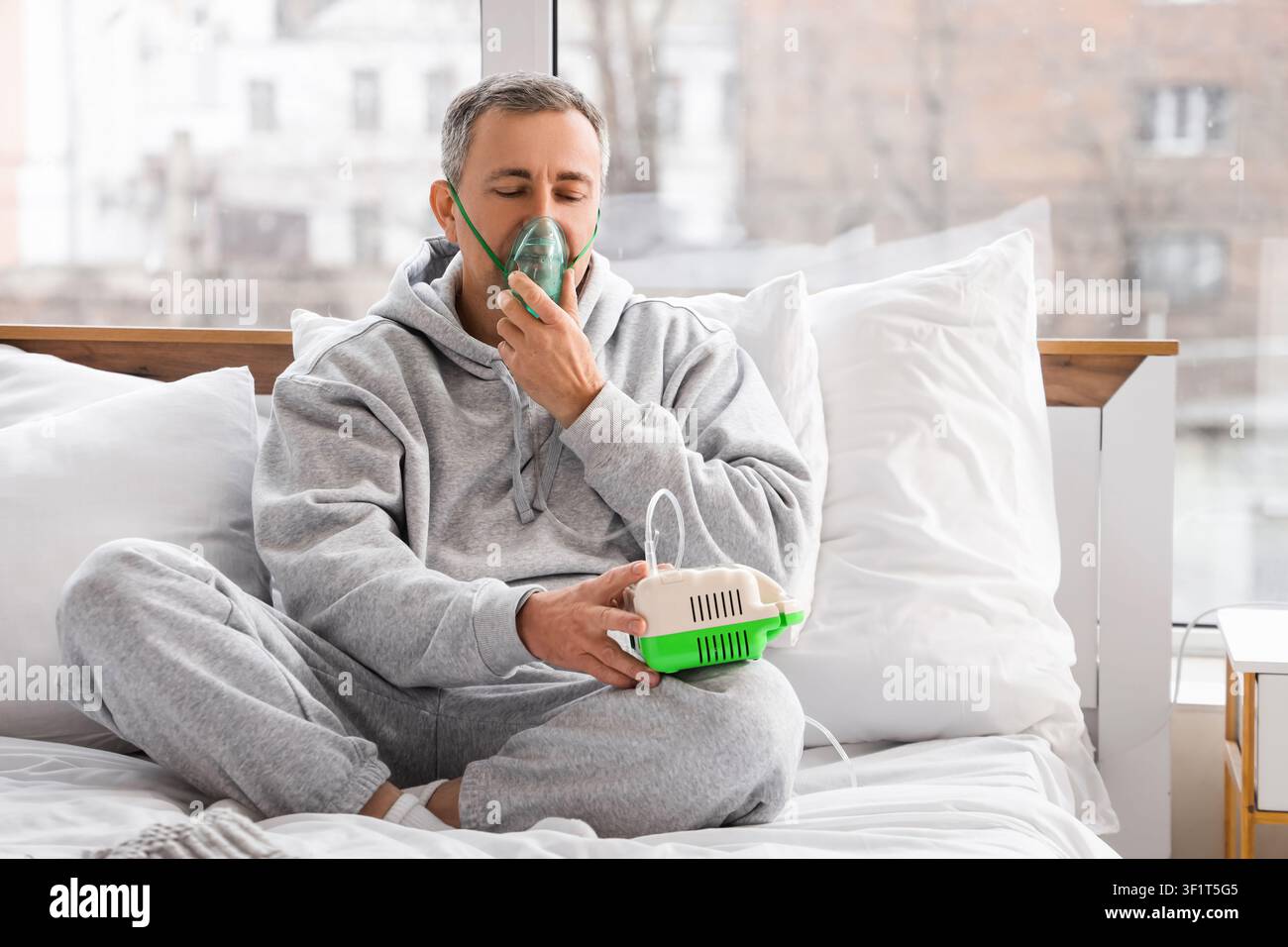 Mature man using nebulizer in bedroom Stock Photo