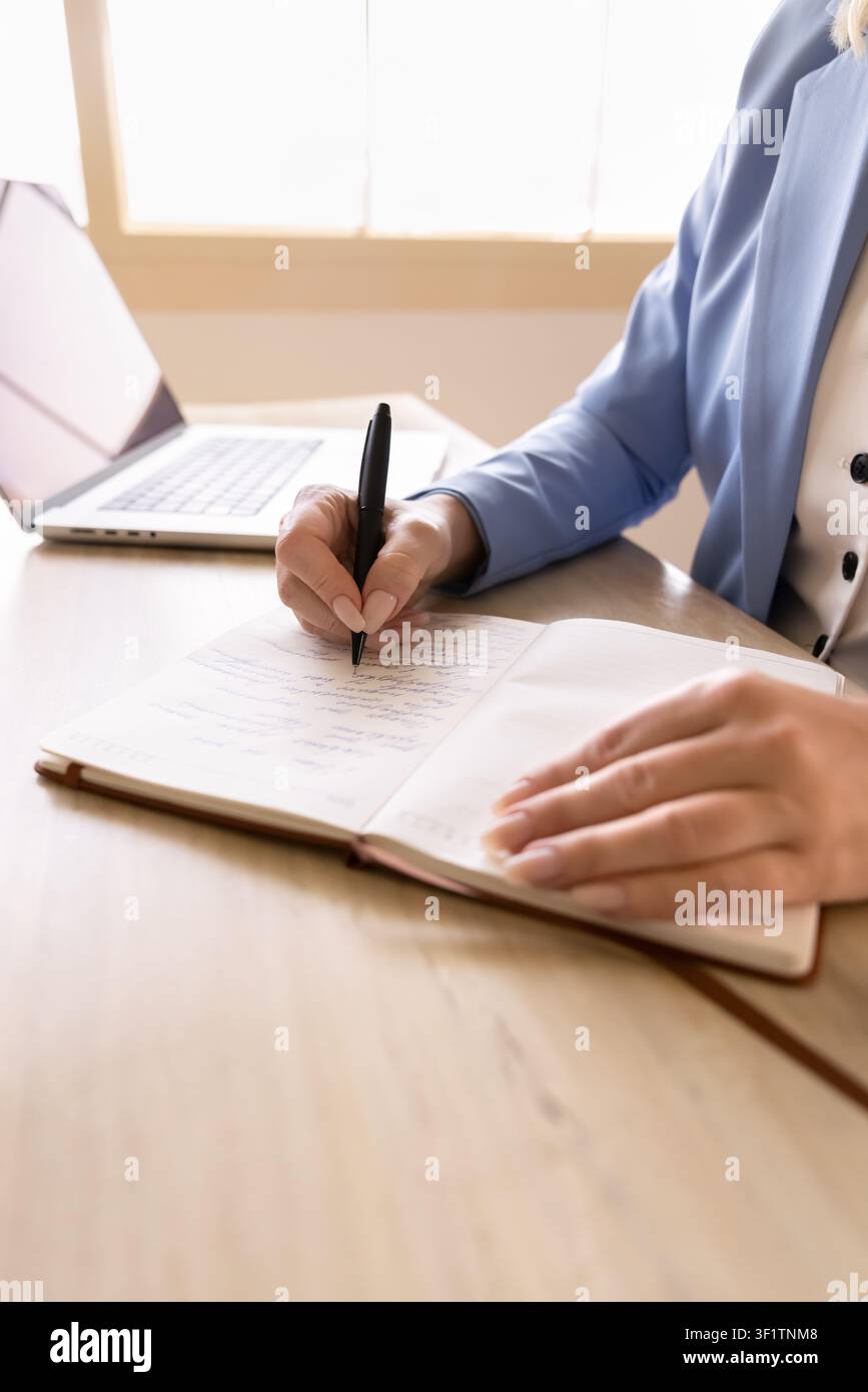 Professional woman writing information in notebook at office desk, closeup Stock Photo