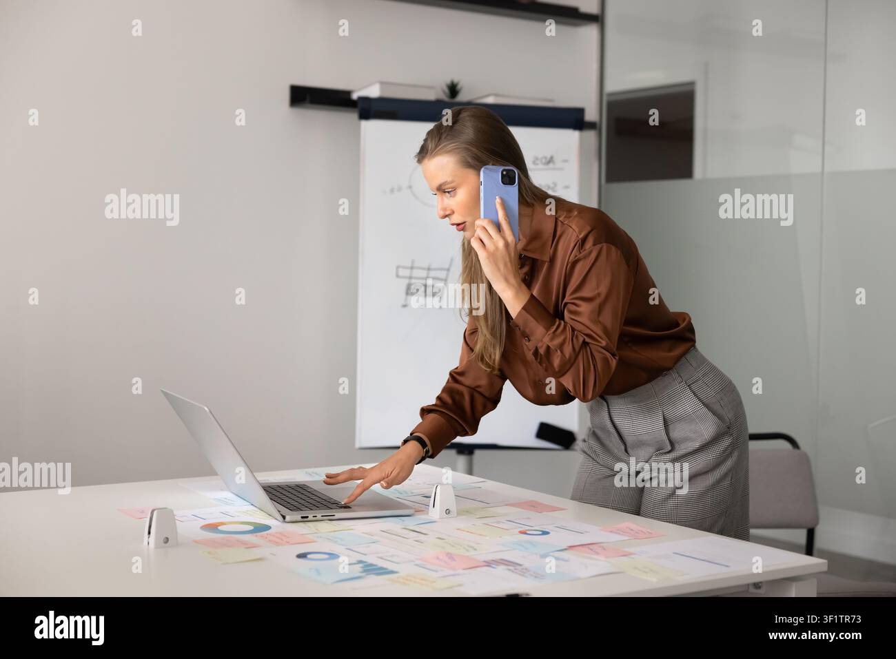 Businesswoman talking on phone while analyzing charts Stock Photo