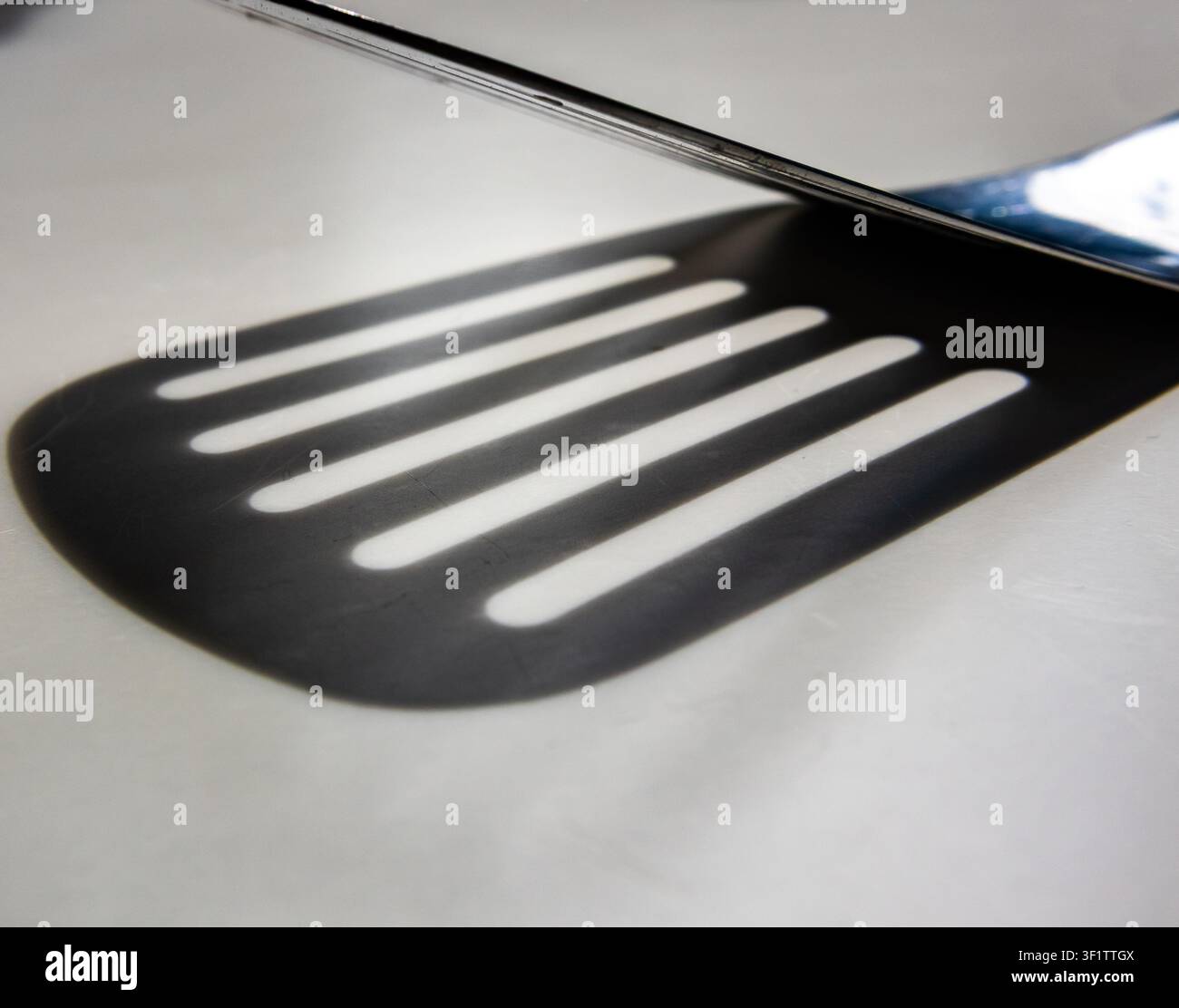 Kitchen spatula edge with parallel slots forming lined pattern in monotone Stock Photo
