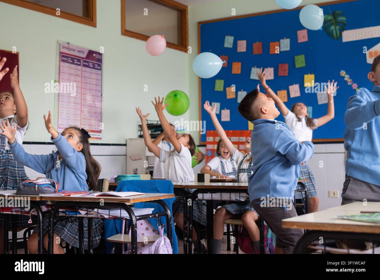 Happy elementary school students playing with balloons during an interactive classroom activity Stock Photo