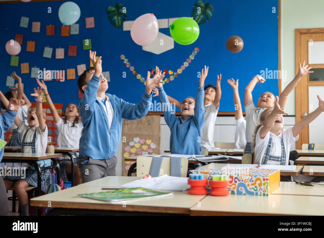 Happy elementary school students playing with balloons during an interactive classroom activity Stock Photo