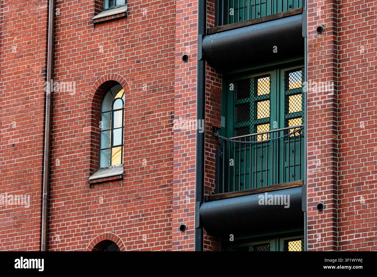 Arched Window on Red Brick Wall Reflecting Golden Sunset Light Stock Photo