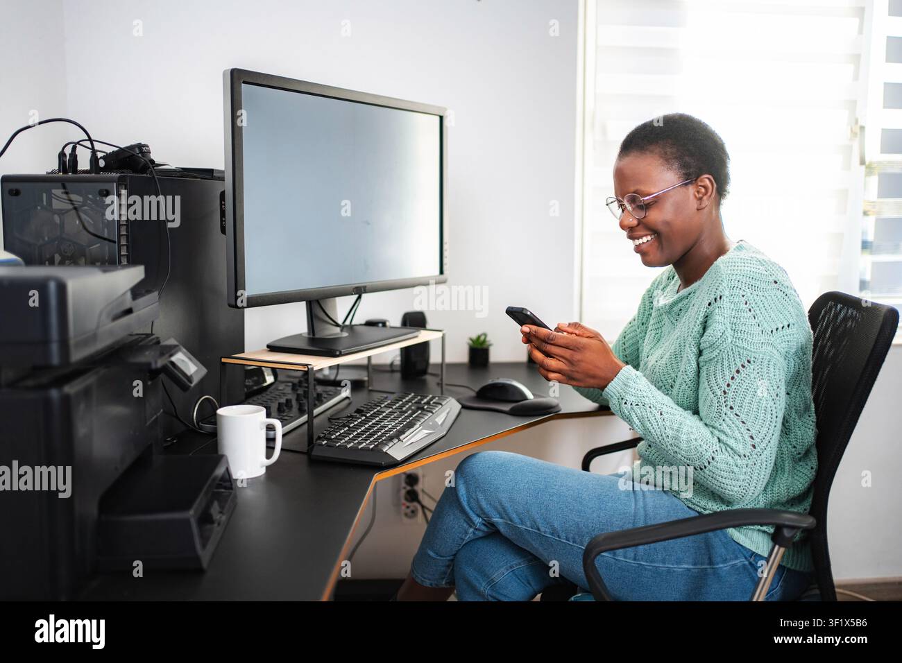 Young black woman using smartphone while working from home Stock Photo