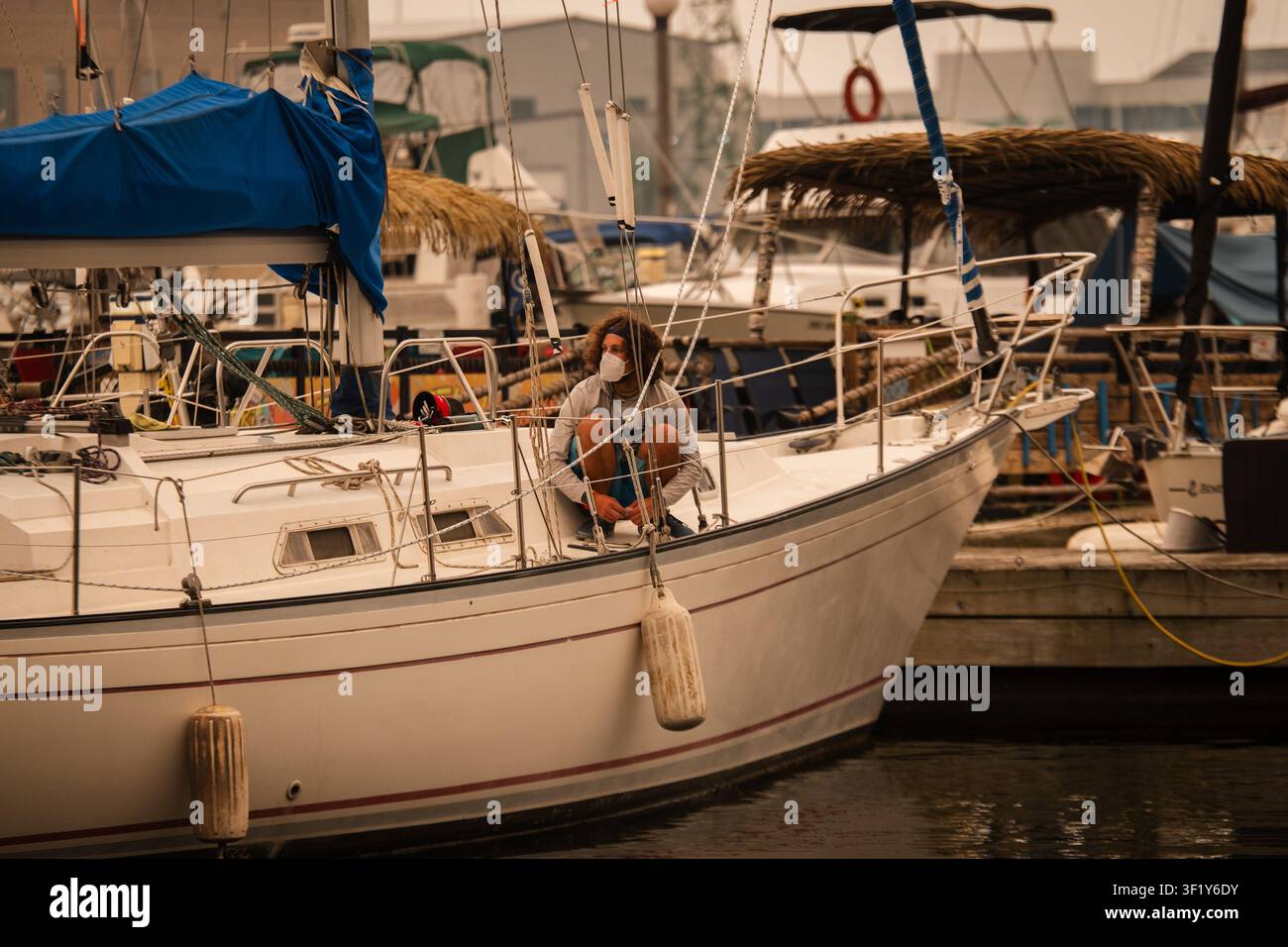 A man in a mask works on his sailboat in Toronto as wildfire smoke