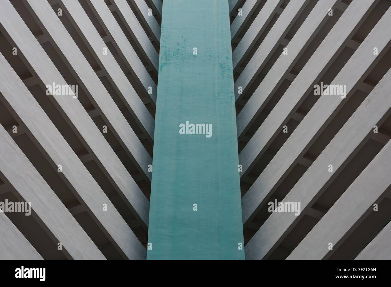Vertical teal panel contrasts with diagonal concrete stripes. Abstract pattern suggests modern architectural design. Angles create strong visual symme Stock Photo