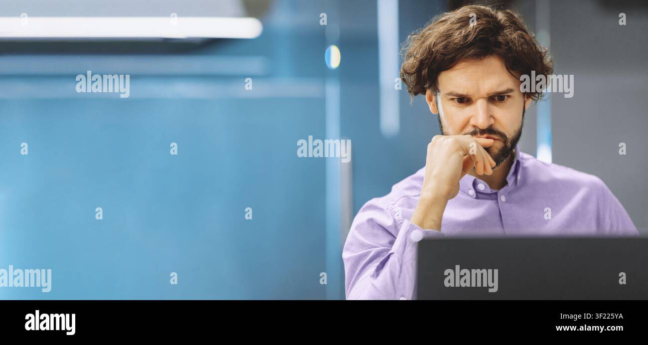 Man Focused on Computer Screen While Working in Office During Daytime Hours Stock Photo