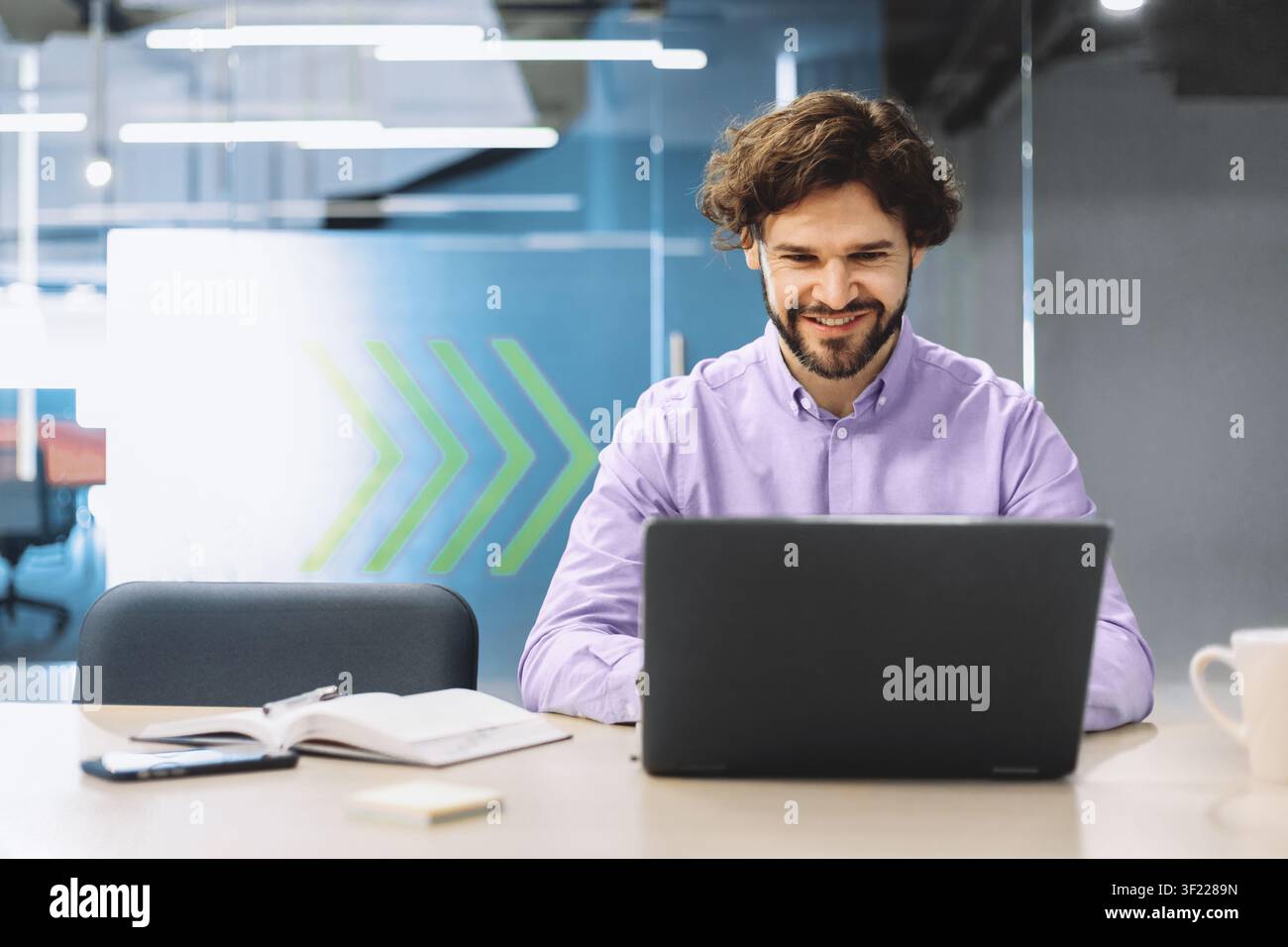 Man Using Laptop in Modern Office Setting During Work Hours Stock Photo
