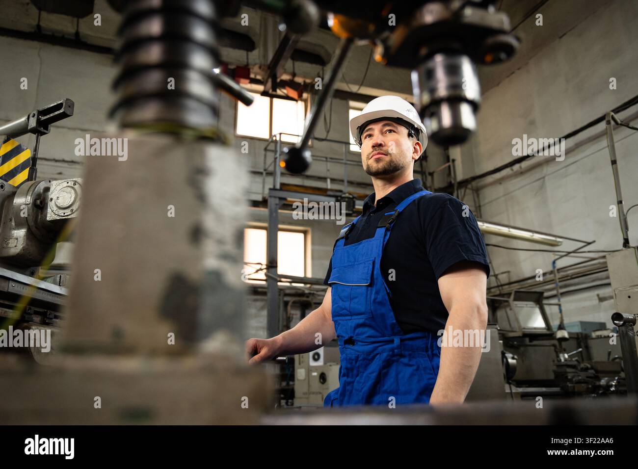 Industrial engineer standing beside CNC machine in modern manufacturing workshop Stock Photo