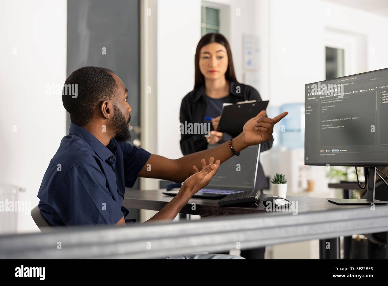 Focused developers work together in a modern startup office, reviewing software information on multiple screens. Team collaboration supports innovation, coding accuracy, and efficient problem solving. Stock Photo
