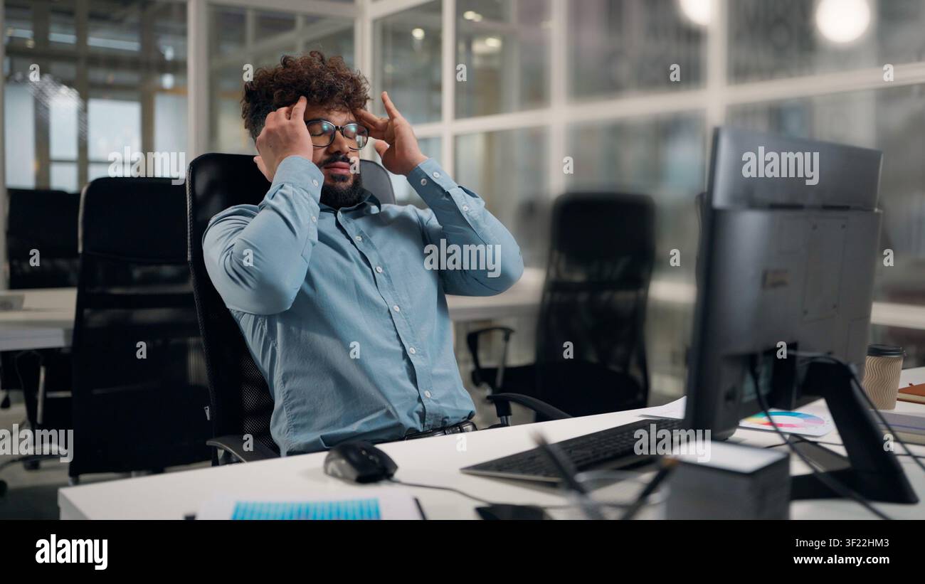 Tired exhausted Arabian ethnic business man working with computer sad suffering with headache problem painful hurt upset stressed businessman work Stock Photo