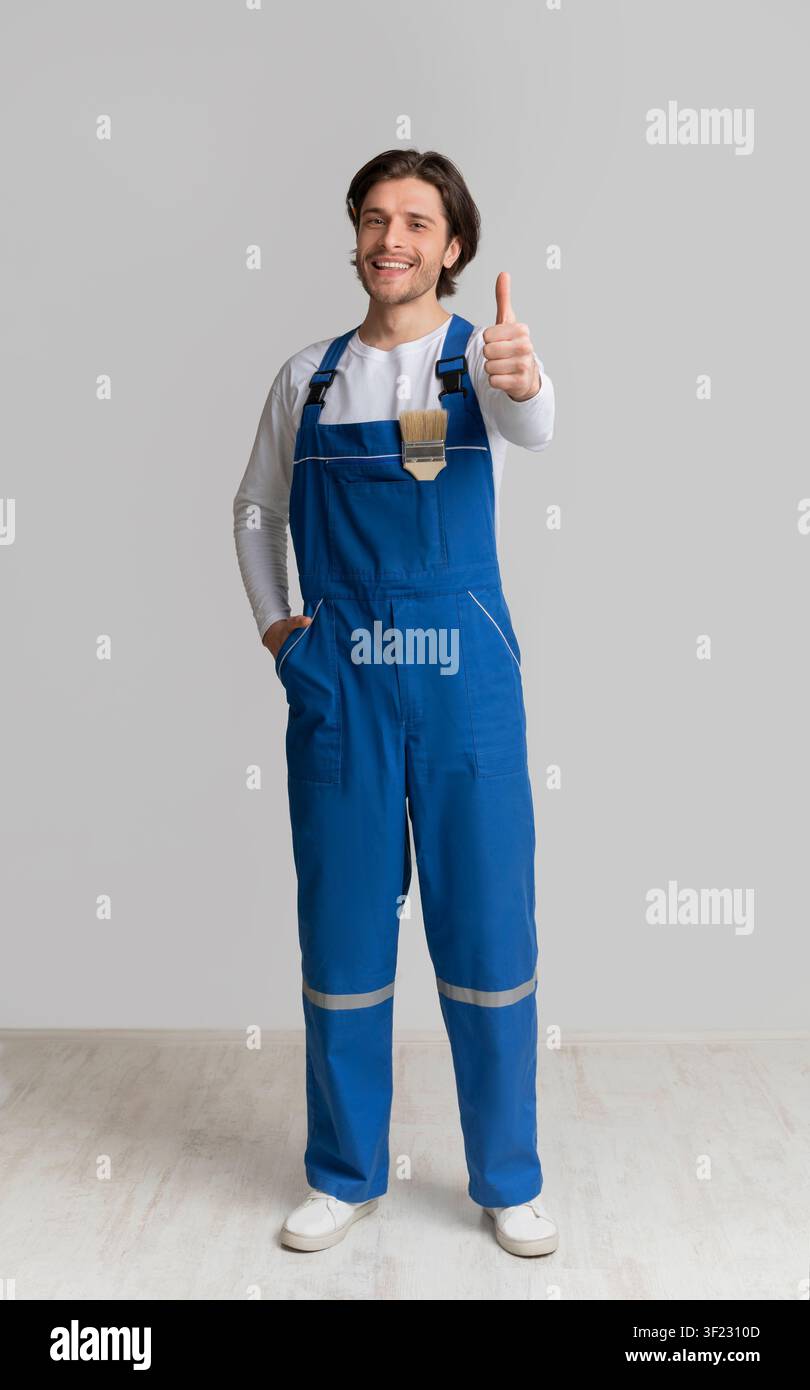 Professional House Painter In Work Uniform Gesturing Thumb Up Stock Photo