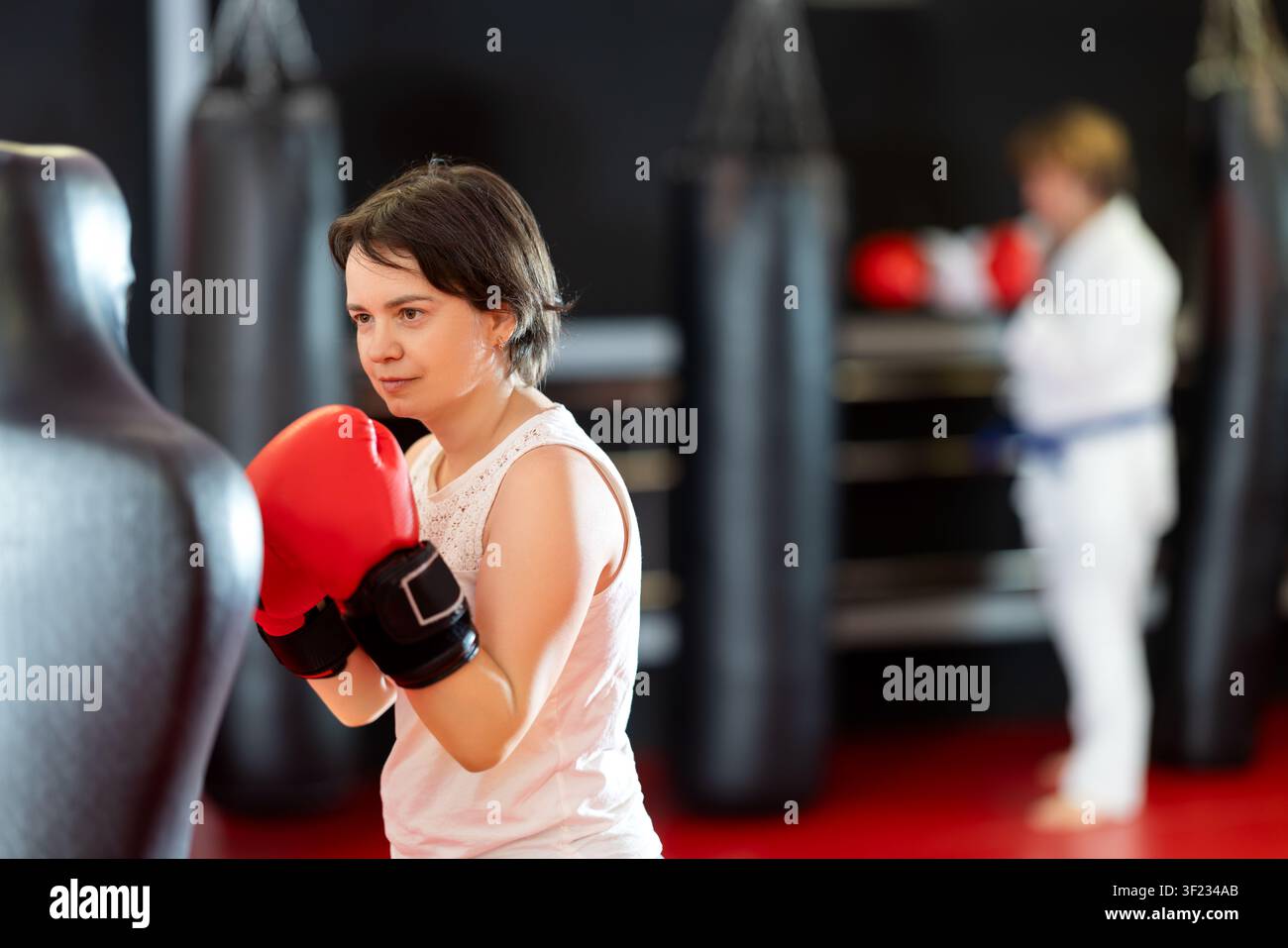 Woman practicing boxing punches on training dummy in gym Stock Photo