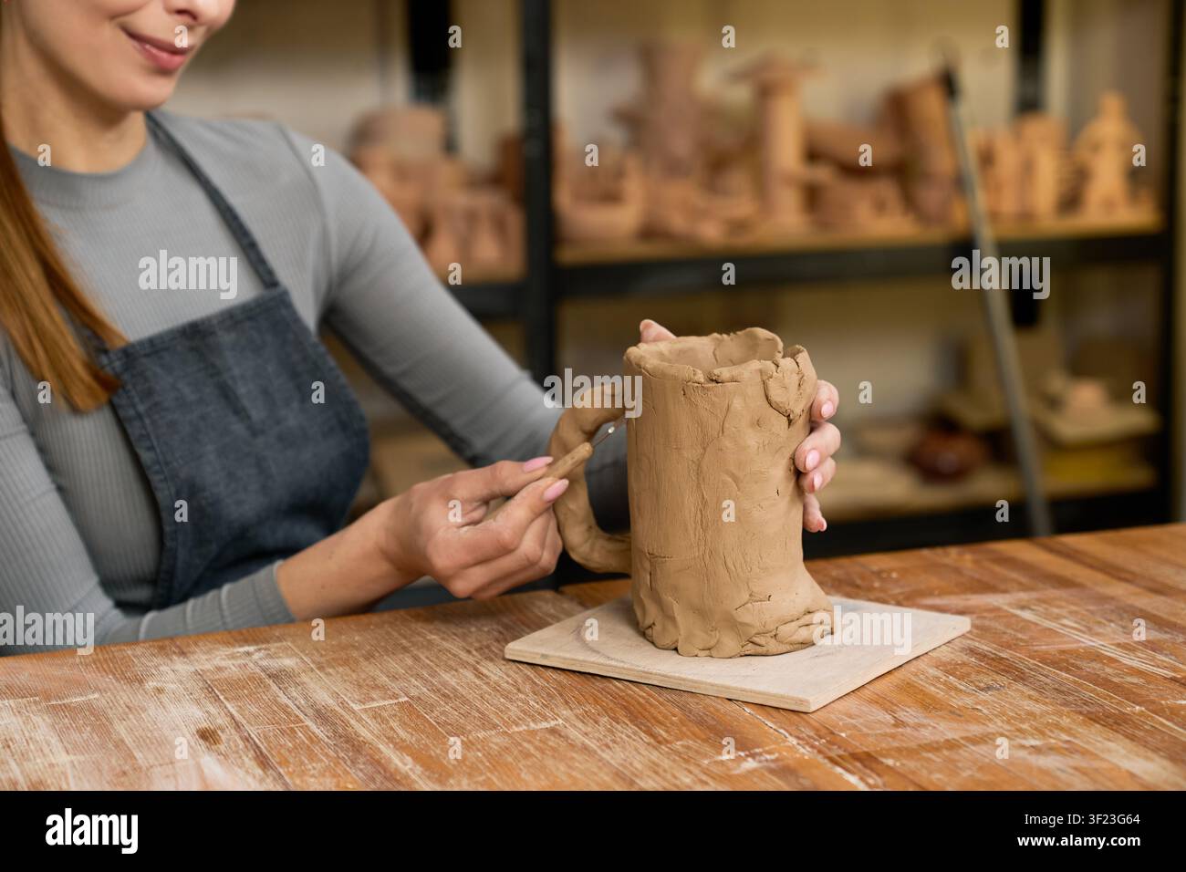 A skilled potter shapes clay into stunning earthenware while enjoying her craft Stock Photo