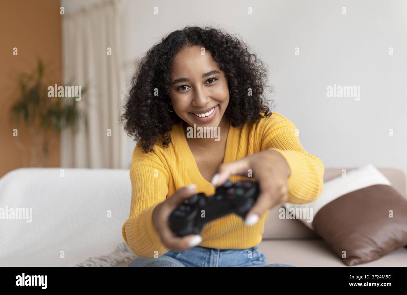 Smiling Young Black Woman Playing Video Game At Home With Game Controller, Relaxation Concept Stock Photo