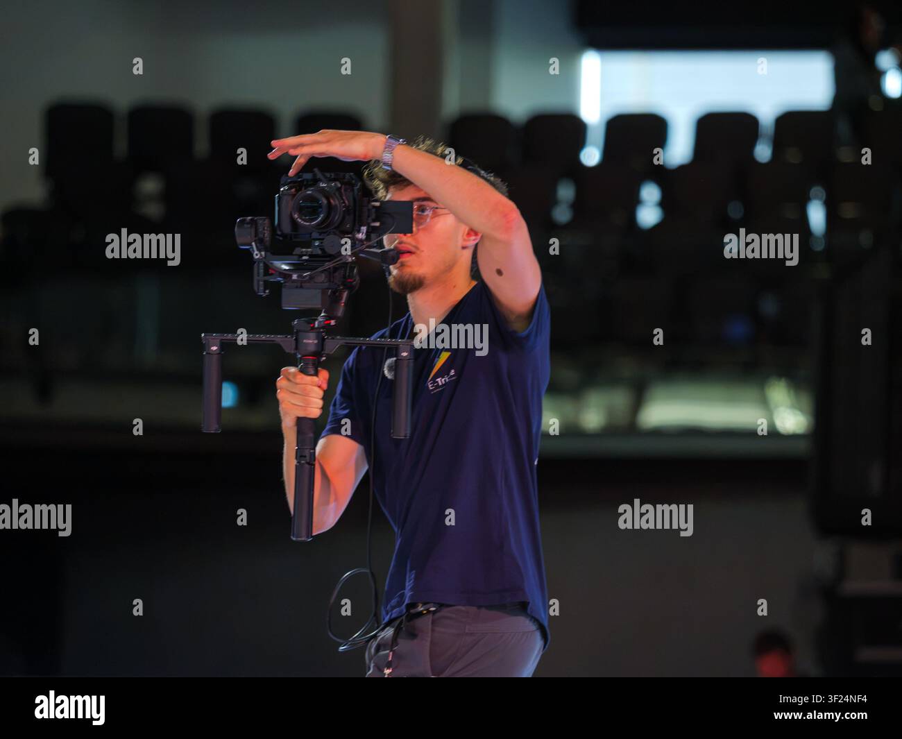 Professional videographer records a breaking competition using a camera mounted on a motorized gimbal. The image shows behind-the-scenes production du Stock Photo