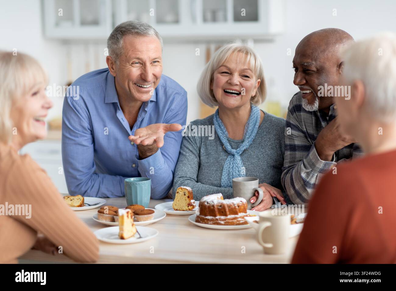 Happy Elderly Couples Enjoying Dessert Together In Bright Kitchen, Smiling And Laughing Stock Photo