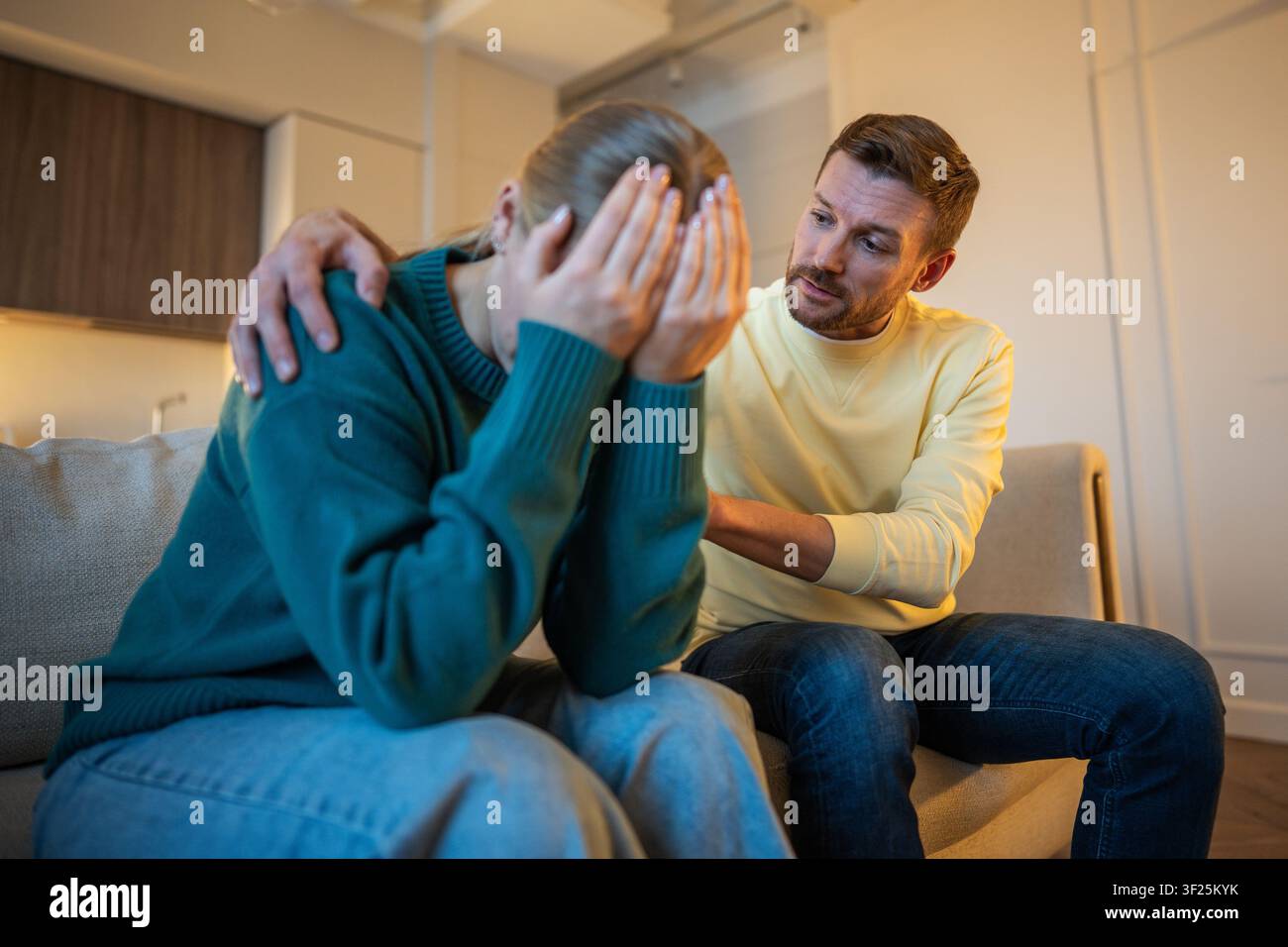 Frustrated exhausted woman sitting on couch hiding face in hands tired of constant husband excuses Stock Photo